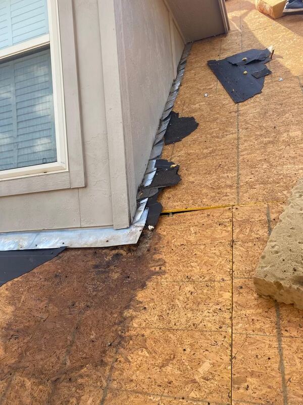 Close-up of new metal roof flashing against stucco wall, clean lines and tight seal.