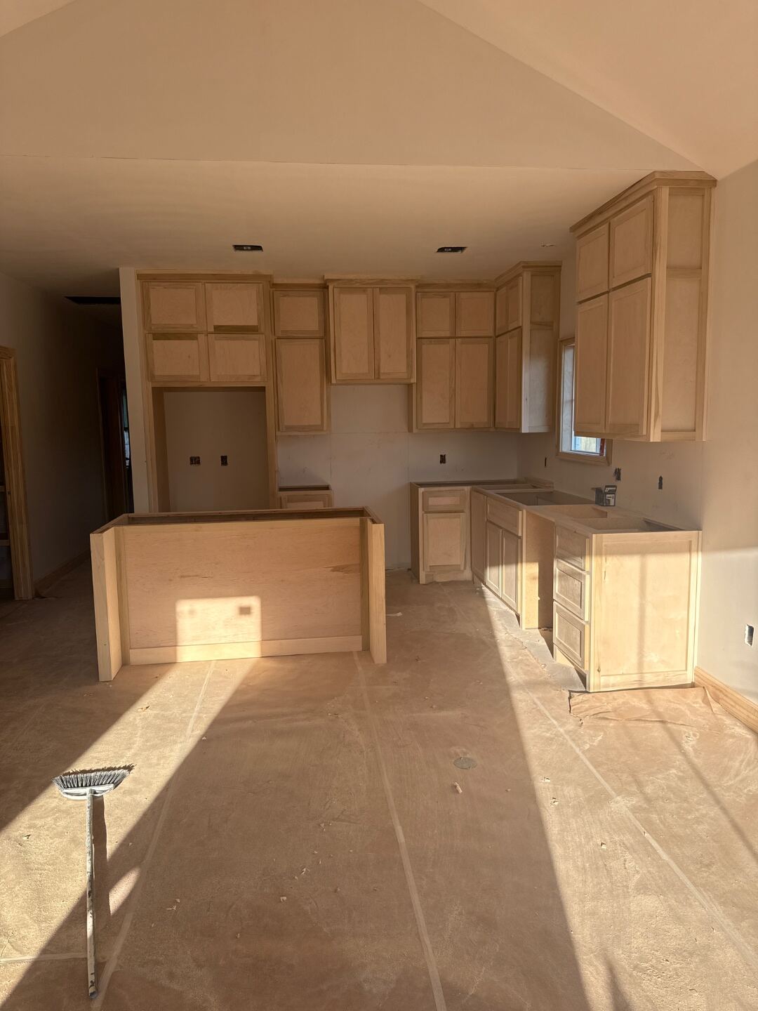 Kitchen cabinets mid-installation with lower bases set, showing the rough plumbing and drawers in progress.